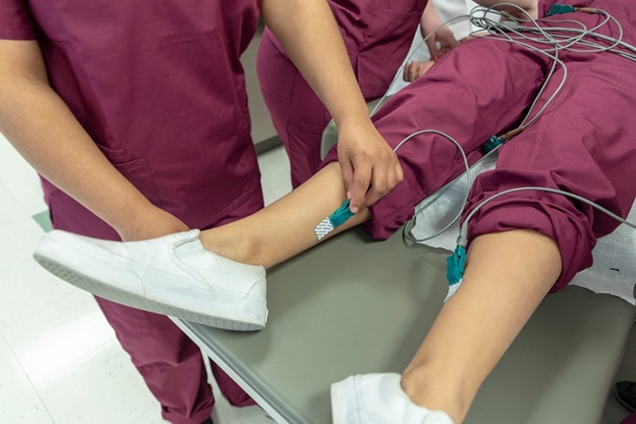 Student attaching a medical device to another student