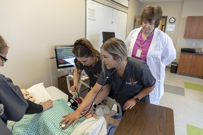Students using a stethoscope on a training dummy