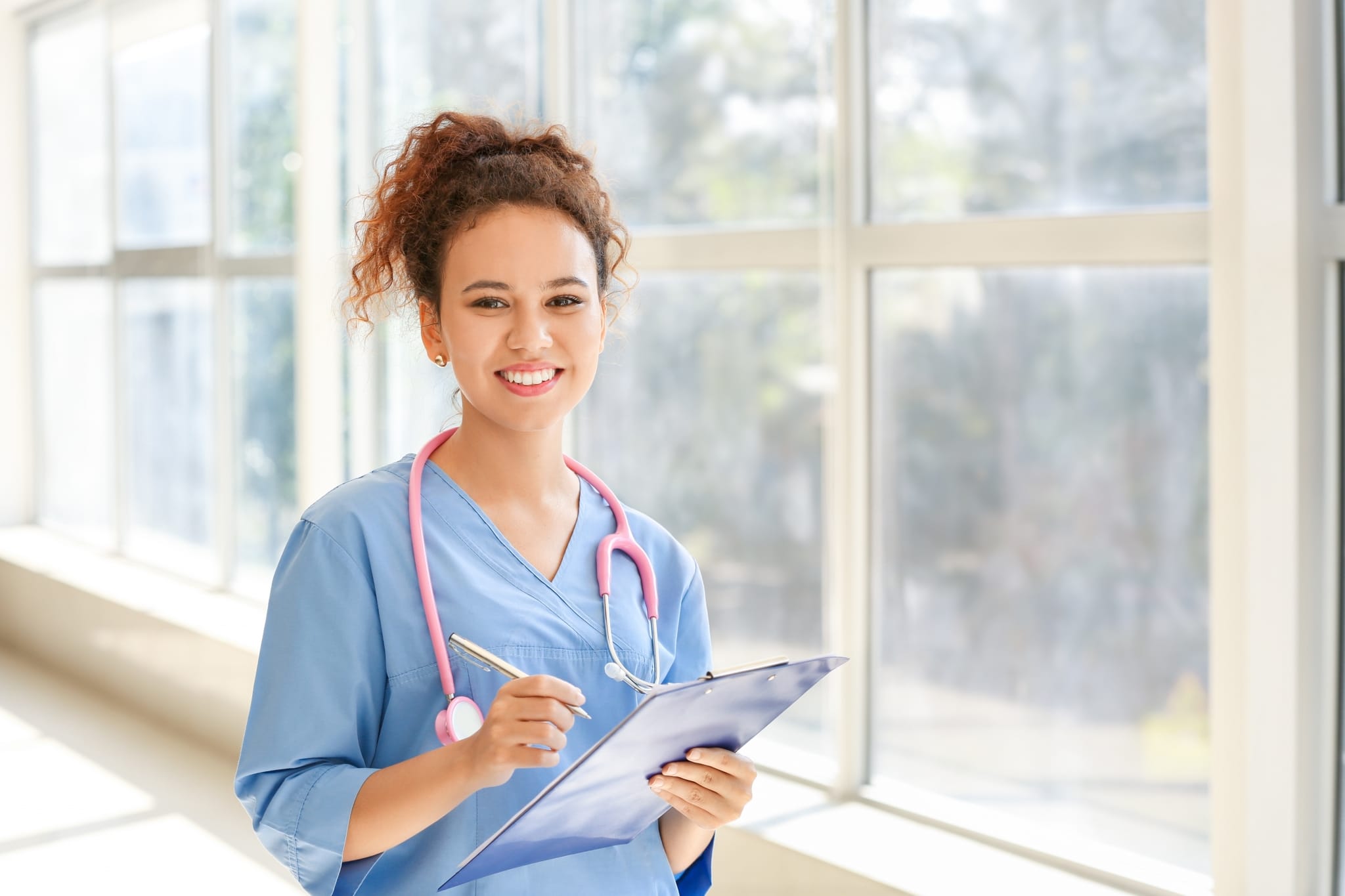 Smiling woman with a stethoscope and clipboard