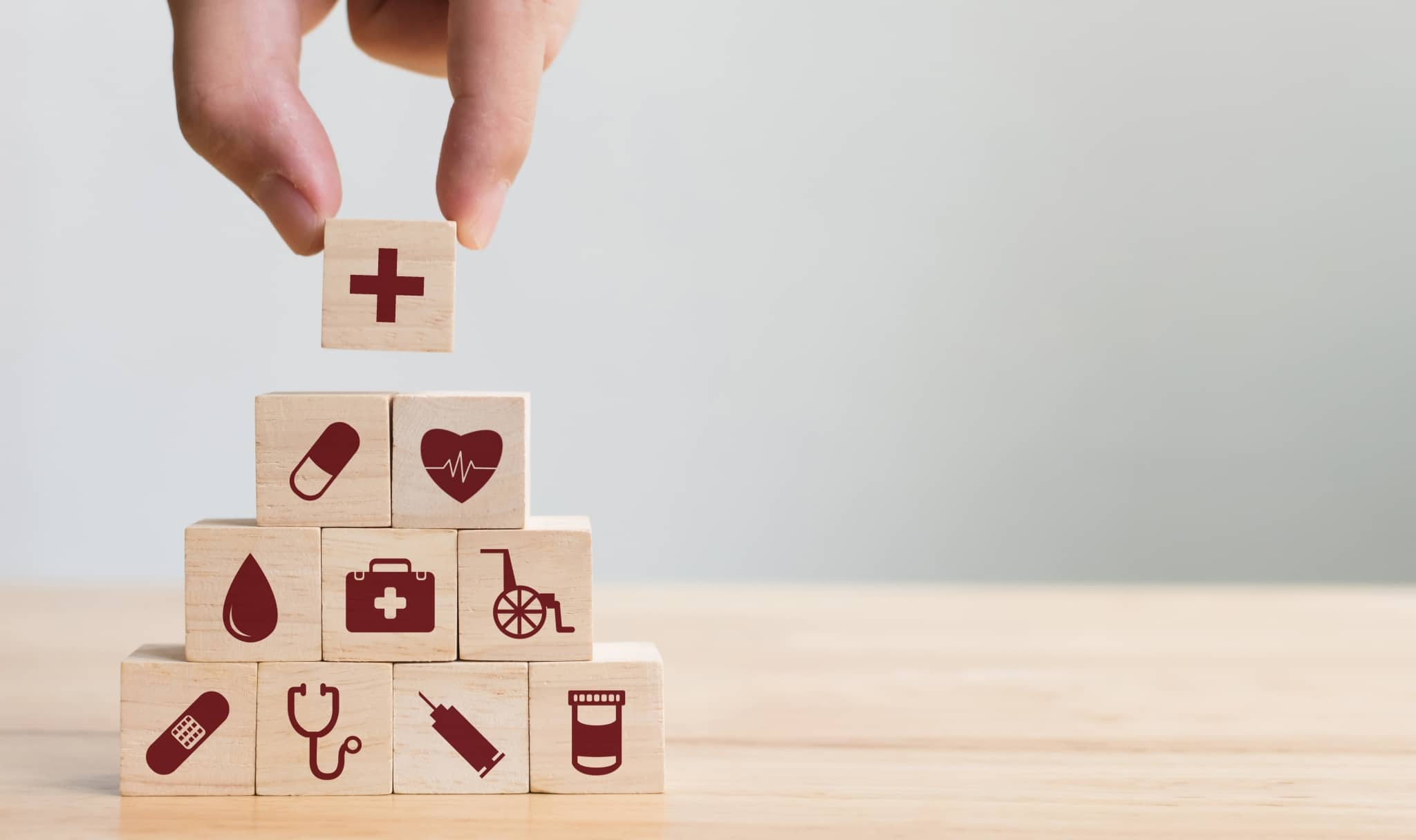 Hand arranging blocks of wood with healthcare symbols
