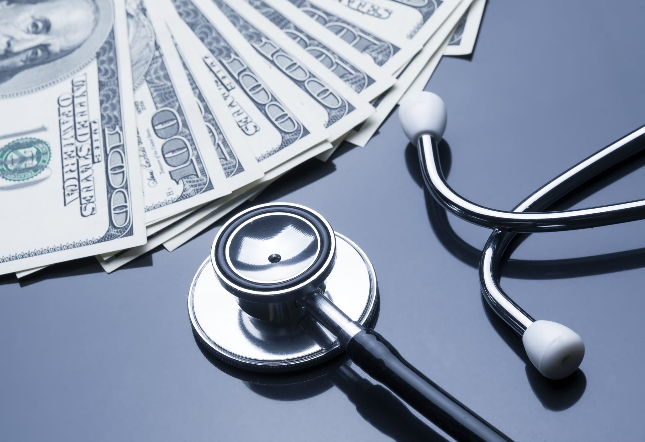 Stethoscope next to 100 dollar bills