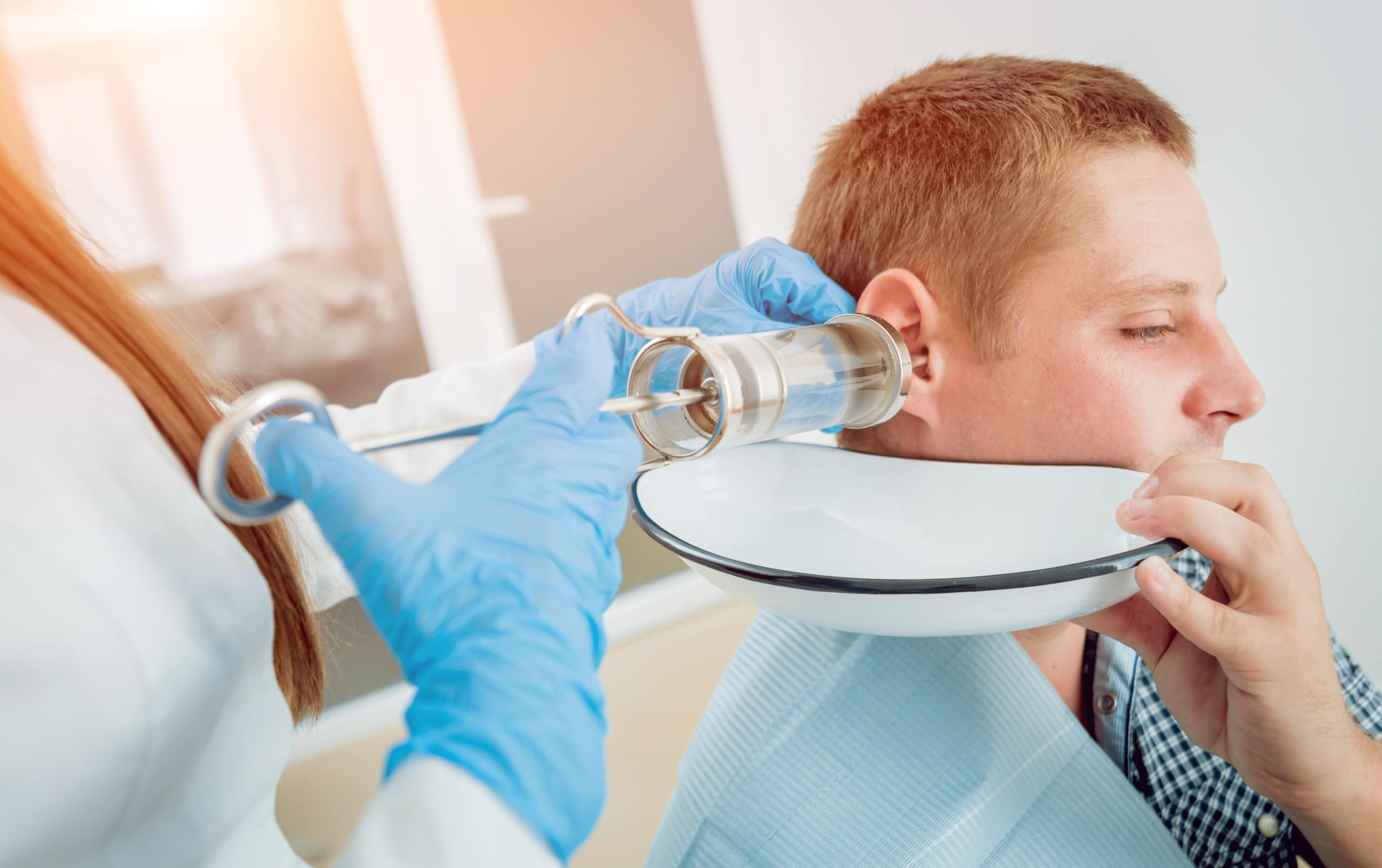Medical professional irrigating a patient's ear