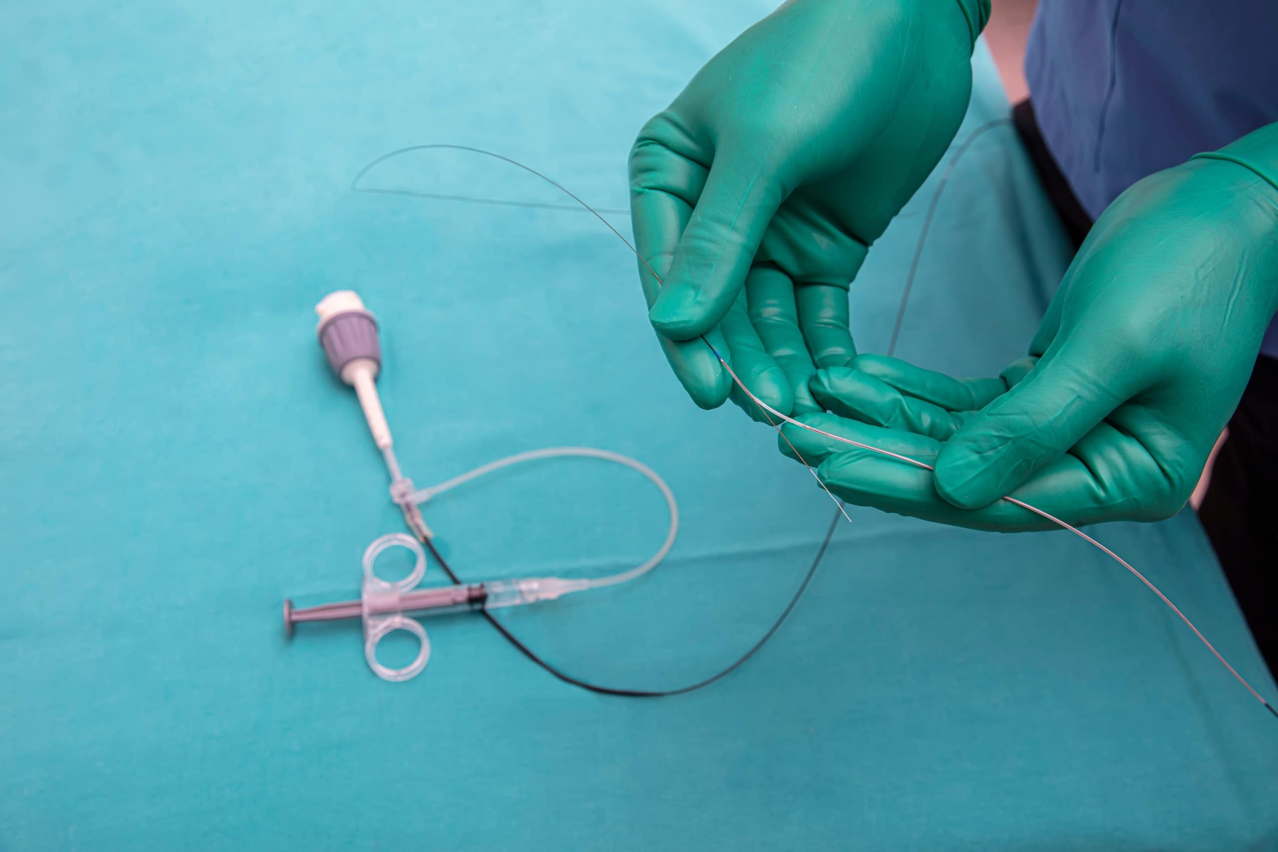Gloved hands holding a catheter
