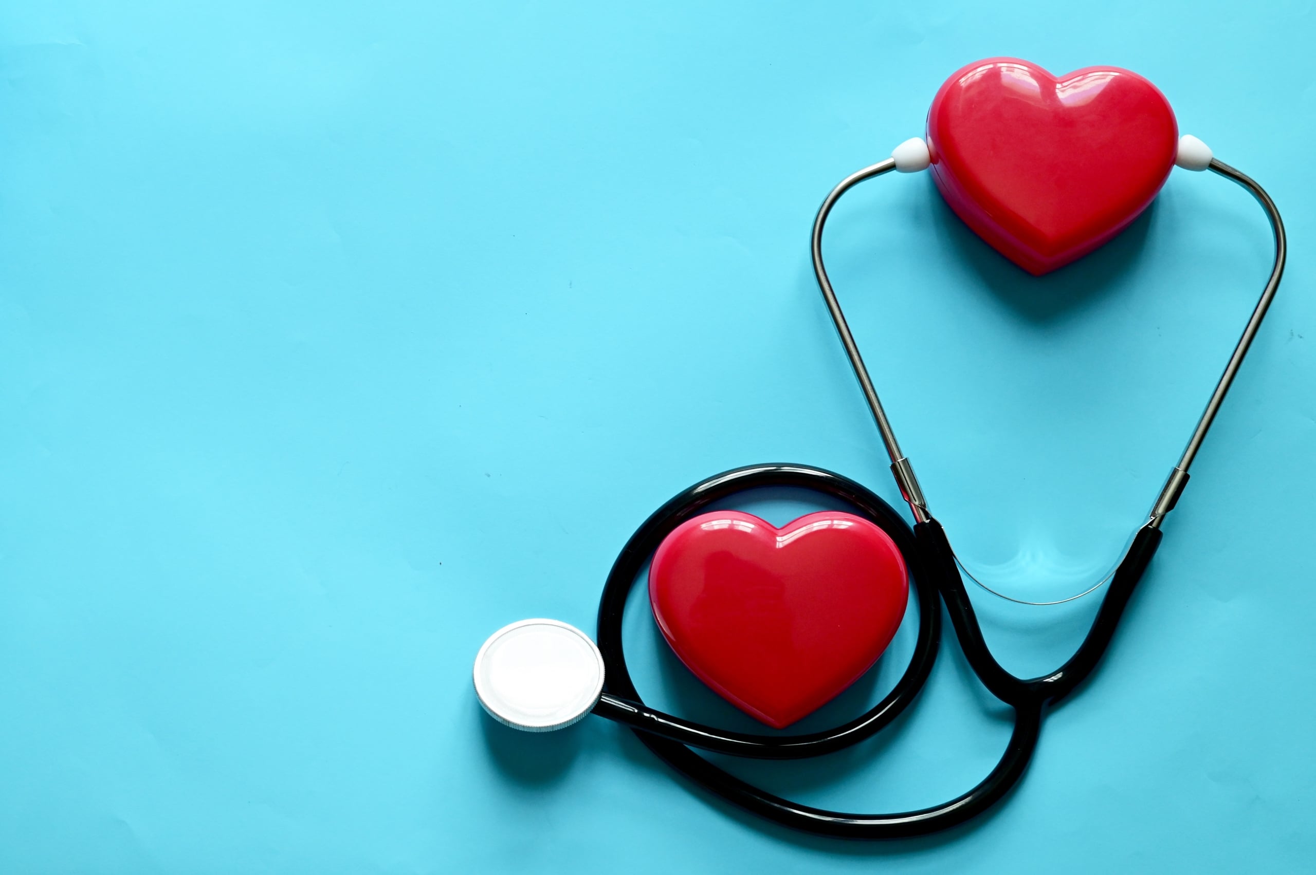 Miniature heart and stethoscope against blue backdrop