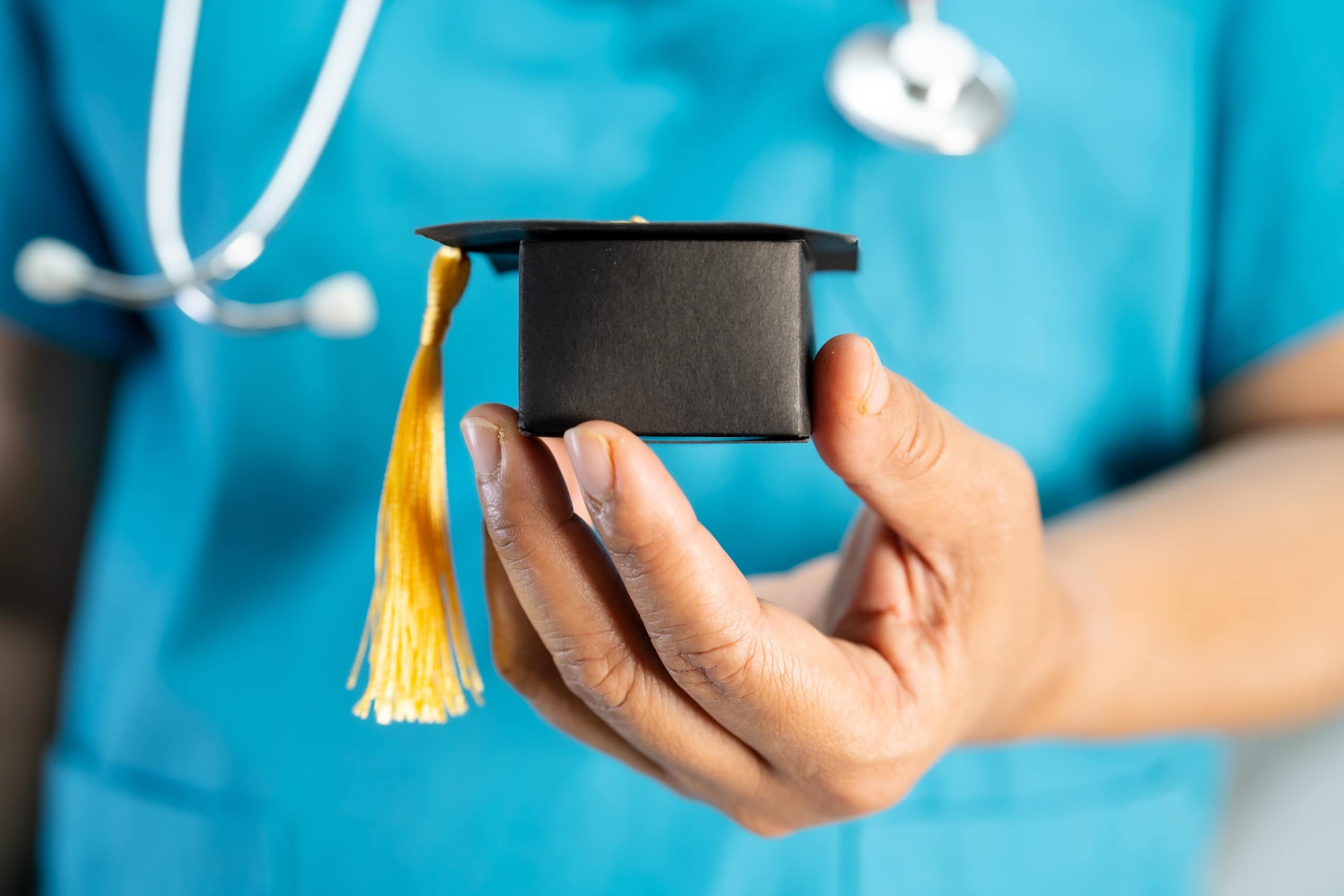 Close up of a medical professional holding a graduation cap