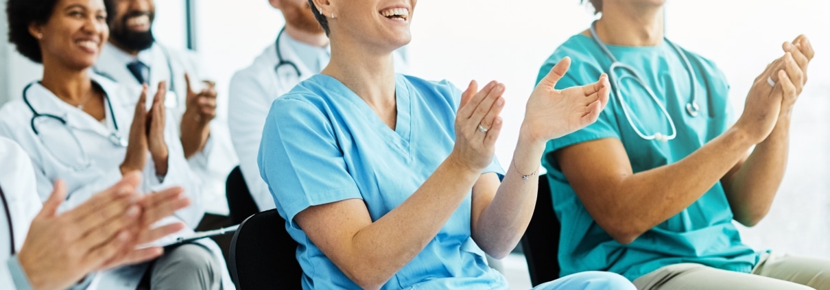 Group of medical professionals clapping while seated