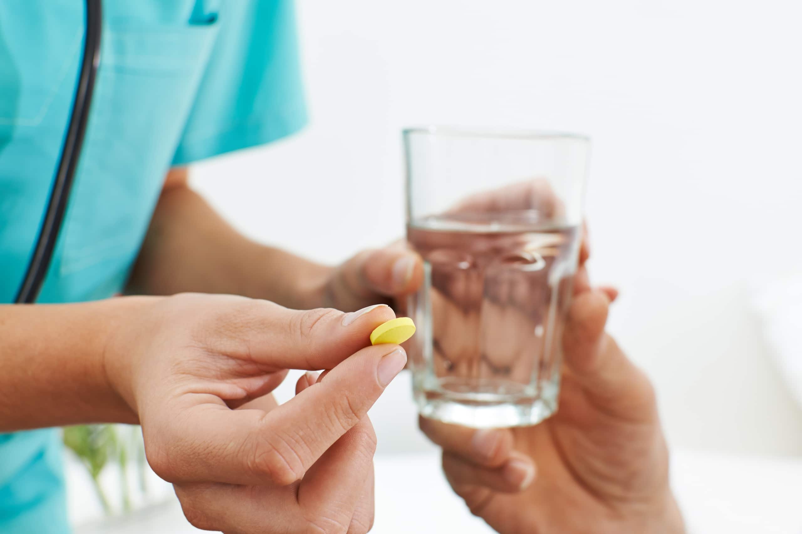 Close up of a nurse giving her patient a pill and glass of water