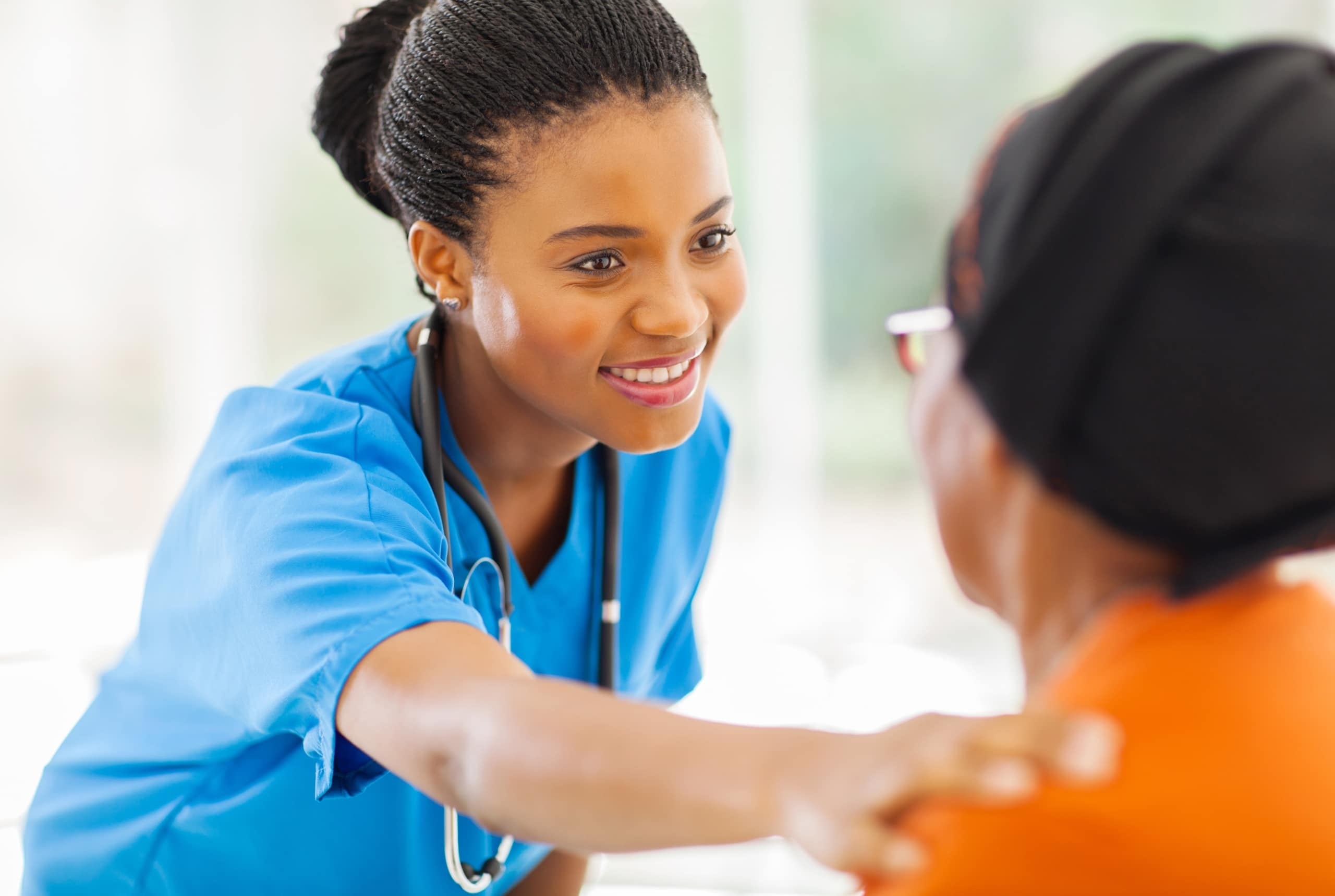 Smiling African-American nurse touching a patient's shoulder