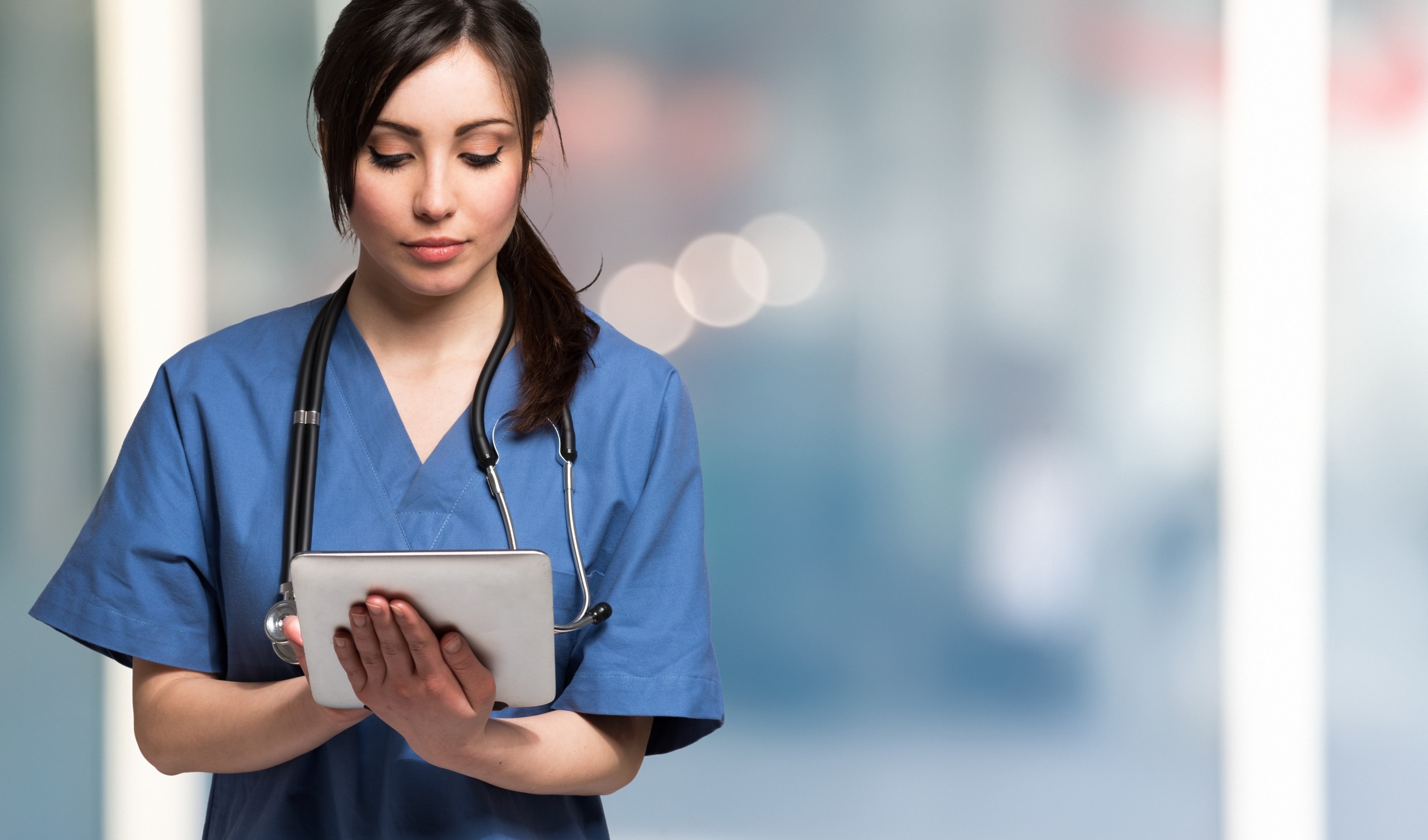 Beautiful nurse looking down at a tablet
