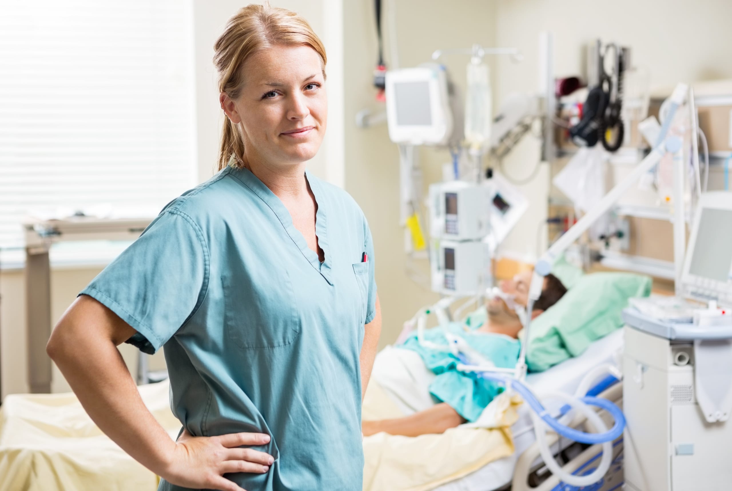 Blonde nurse standing beside an intubated patient