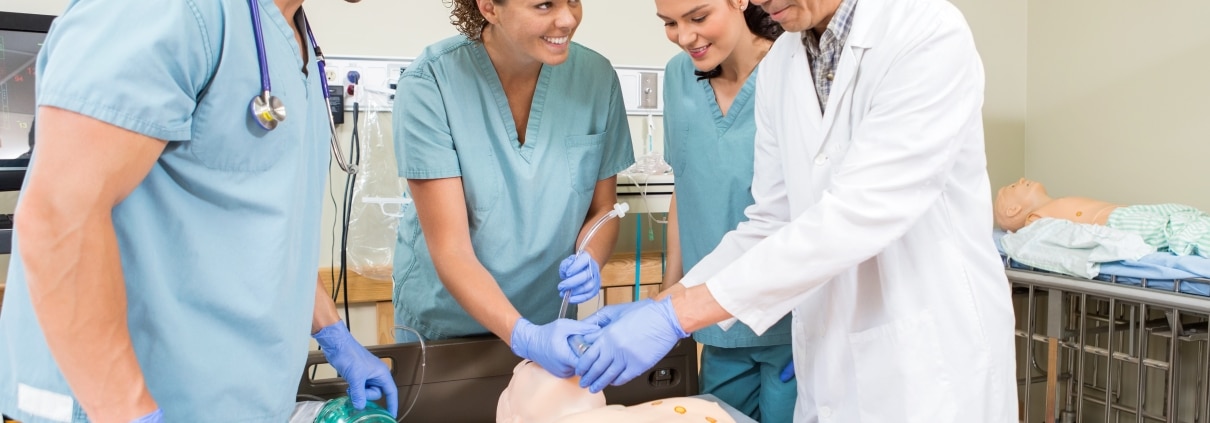 Asian instructor with students using a medical mannequin