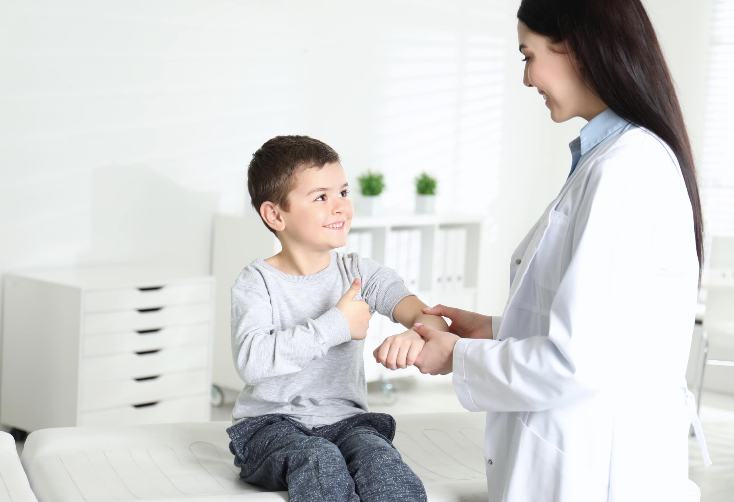 School nurse holding the arm of a smiling little boy