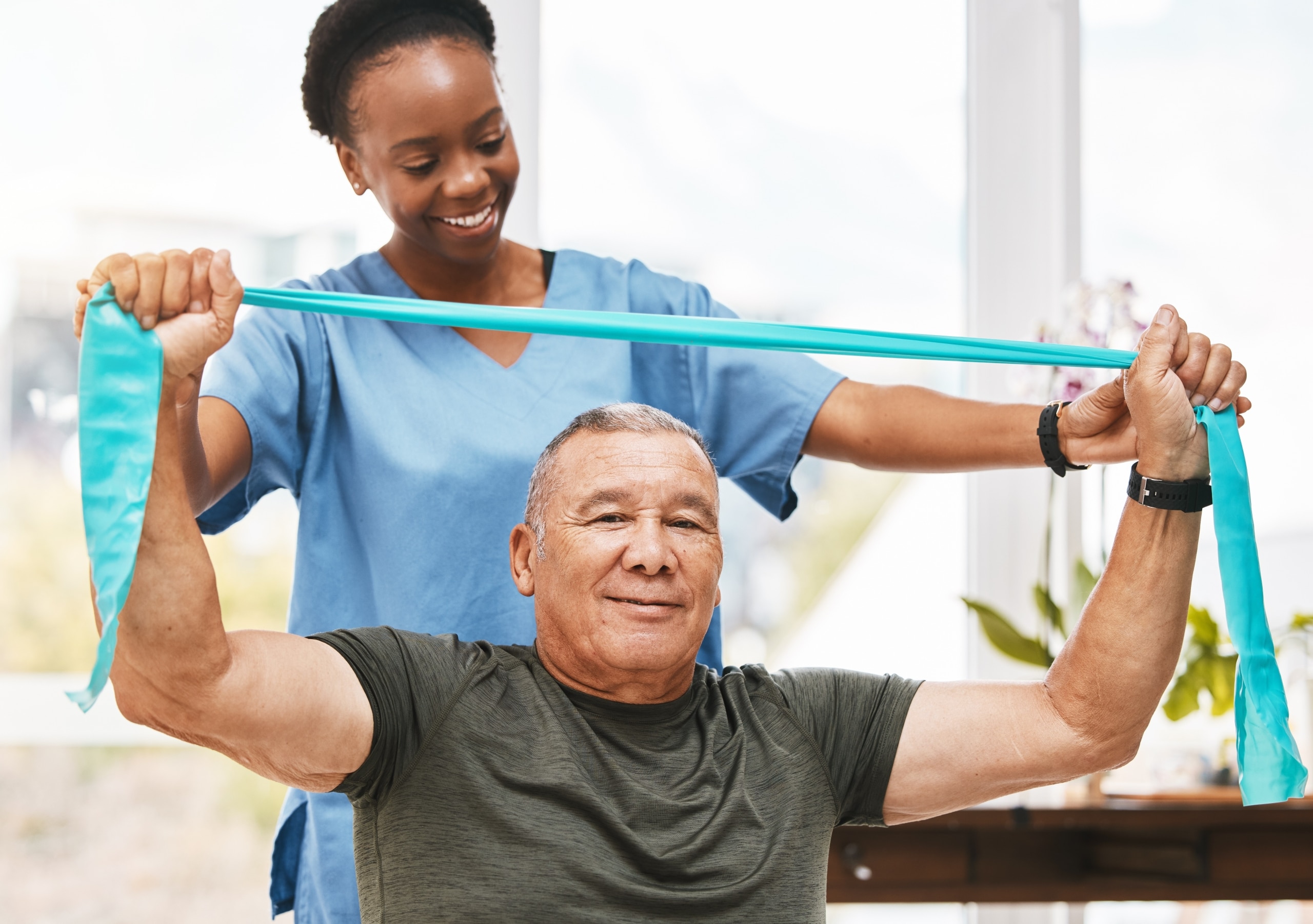 Occupational Therapist Assistant helping a man use an exercise band