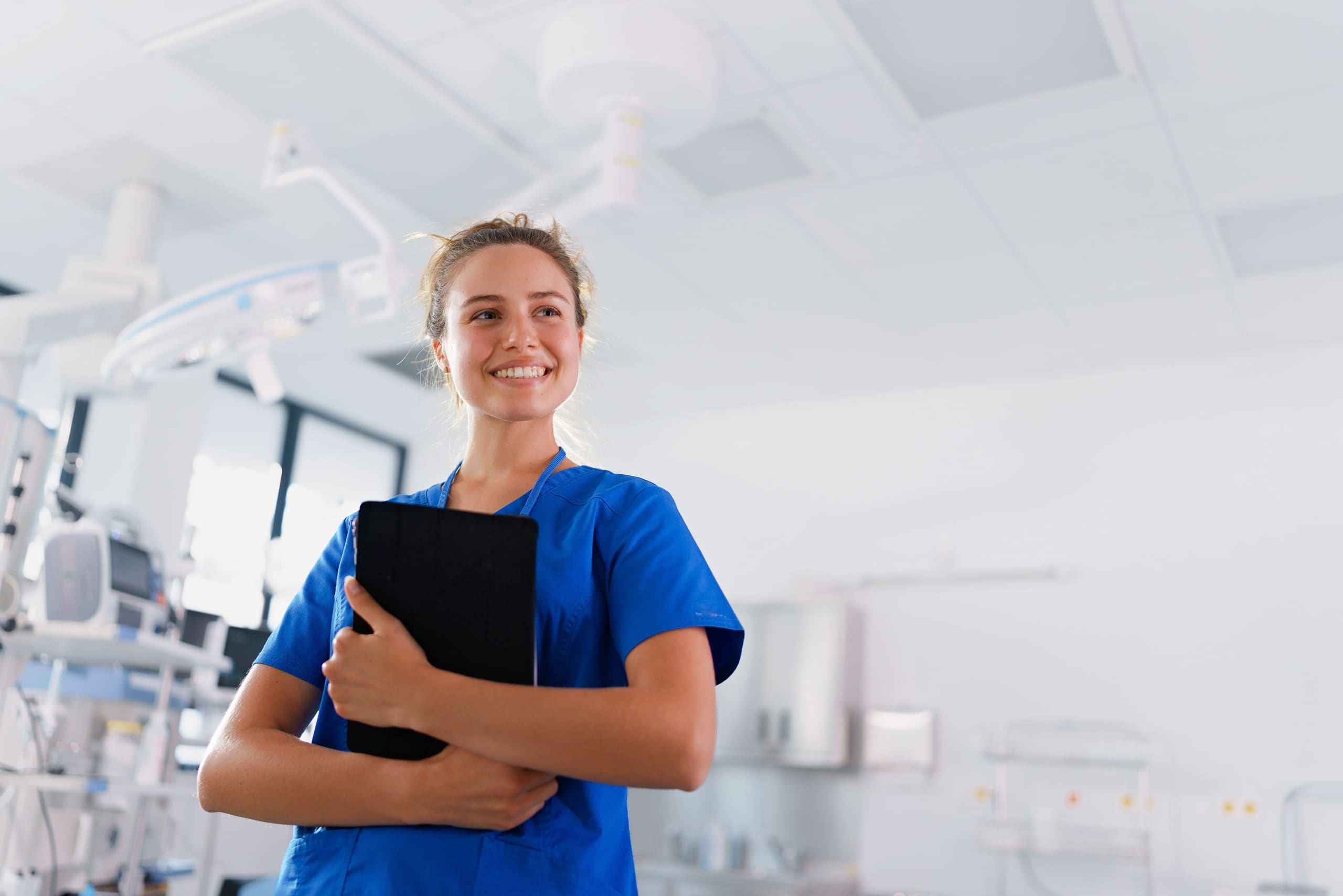Smiling blonde nurse in blue scrubs