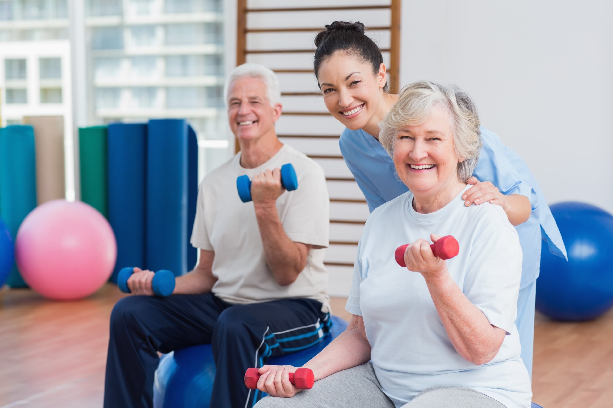 Physical Therapist Assistant helping elderly patients use weights