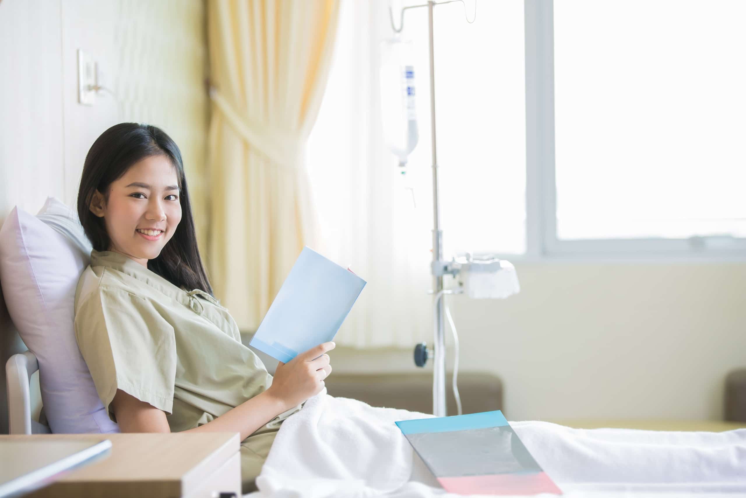 Female Asian patient smiling in a hospital bed