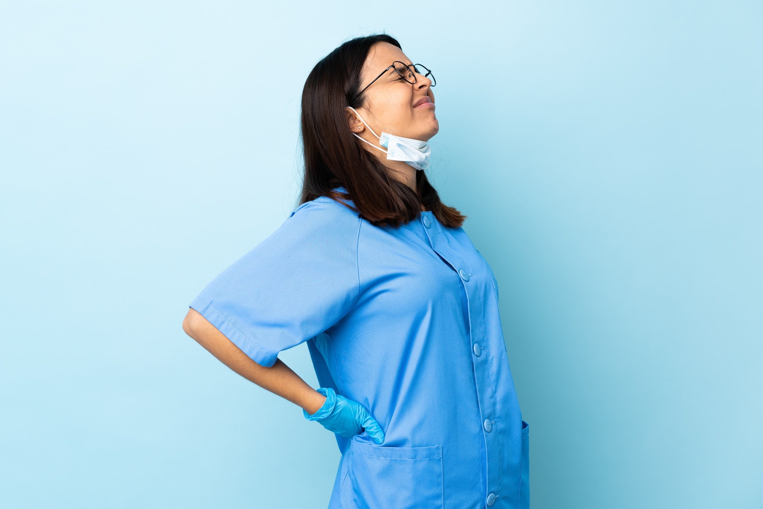 Nurse with glasses touching her back in pain