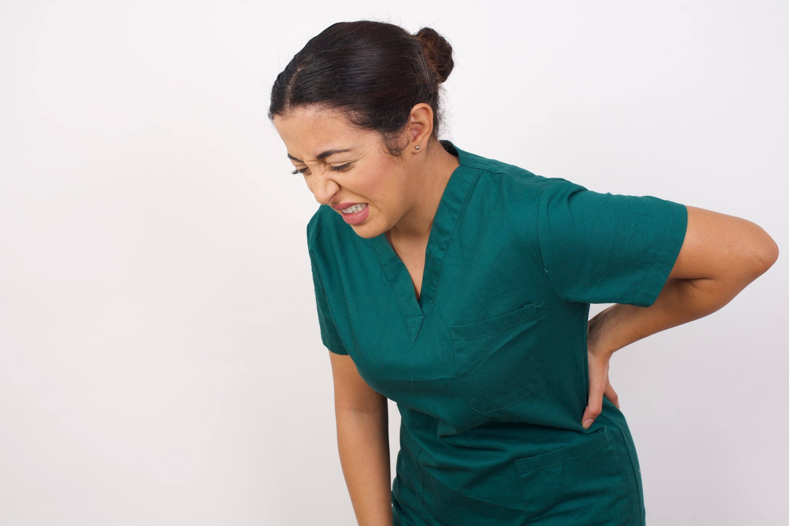 Nurse in green scrubs holding her back in pain