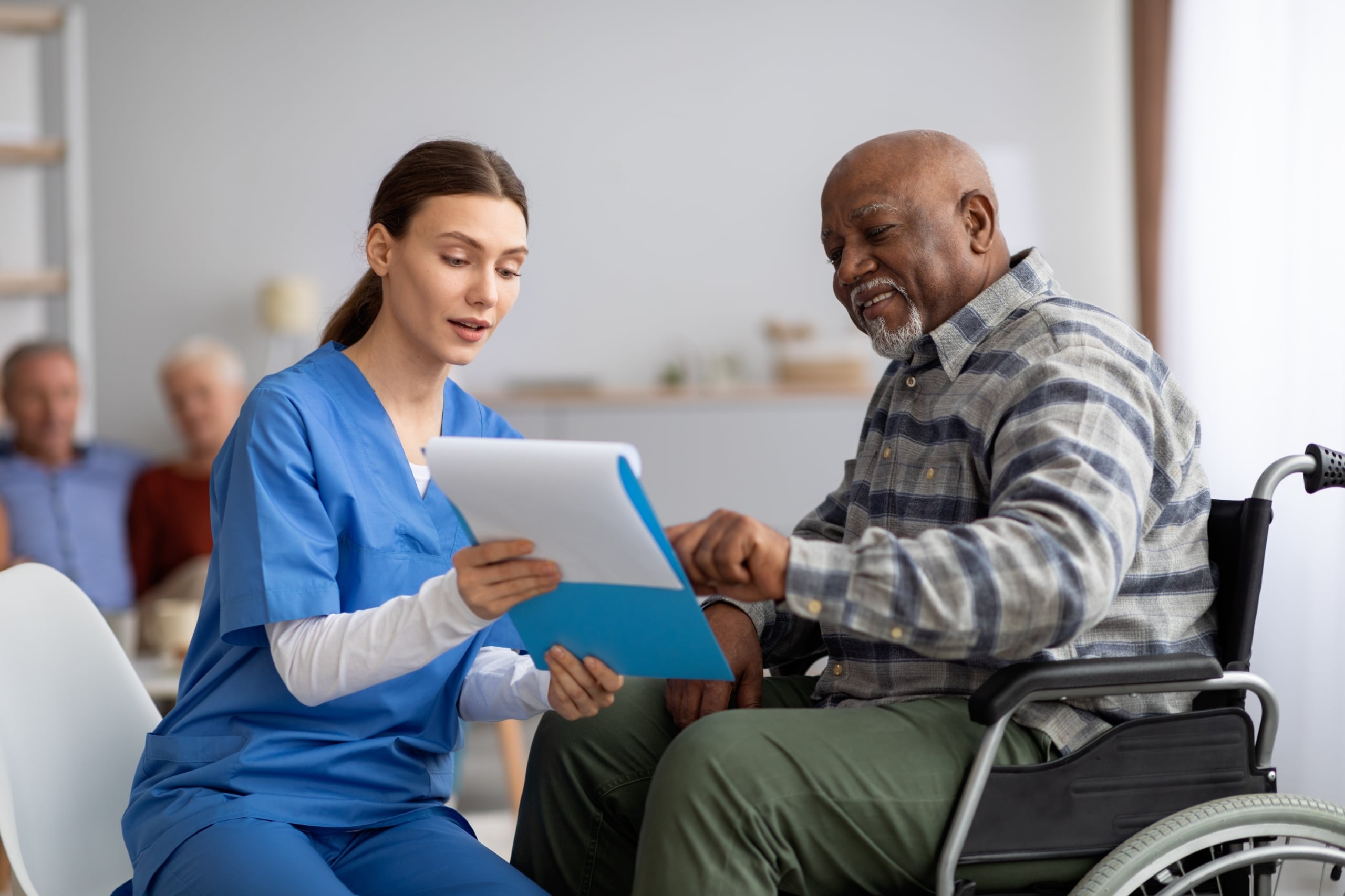 Medical professional helping an older man fill out paperwork