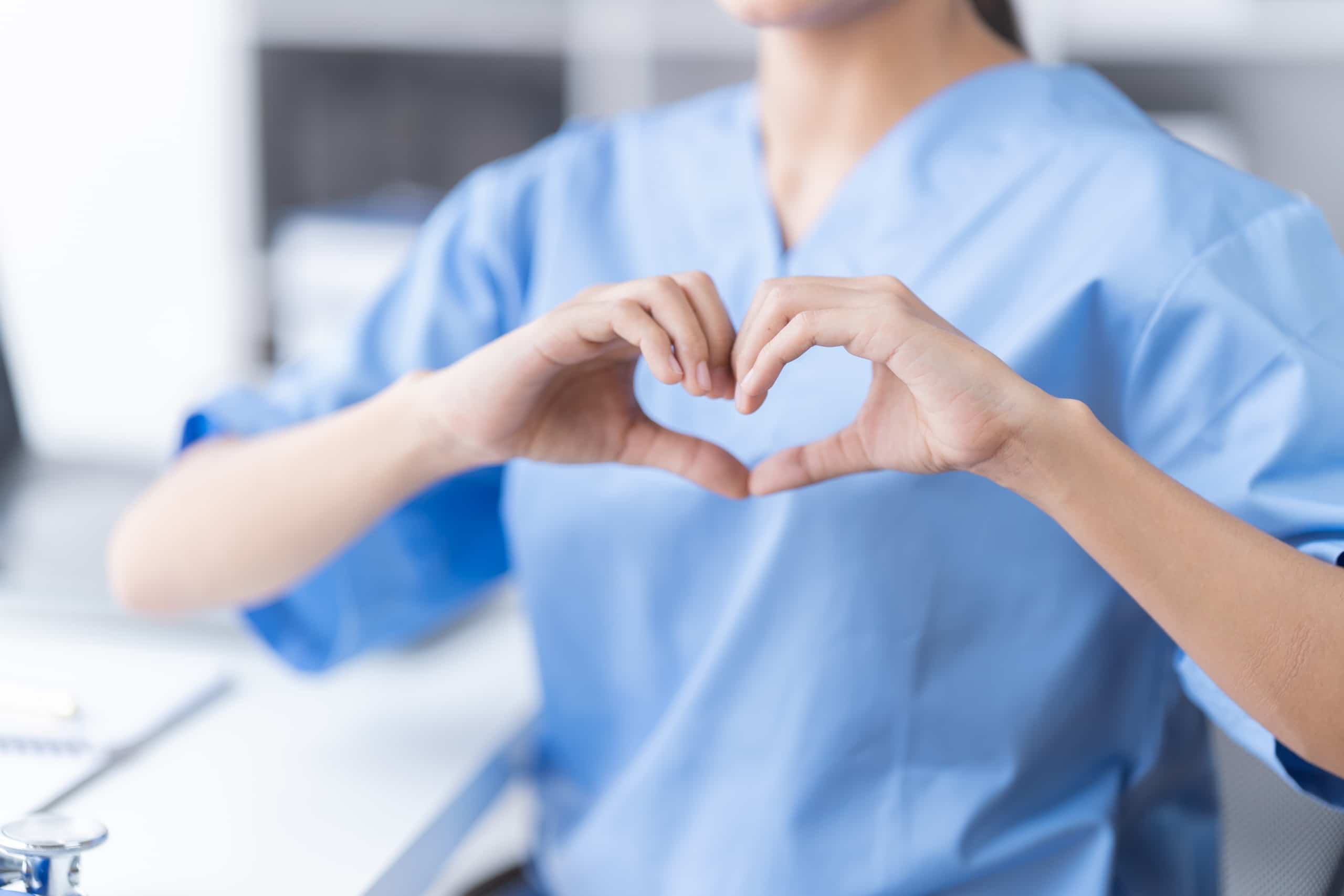 Close up of a nurse forming a heart with their hands