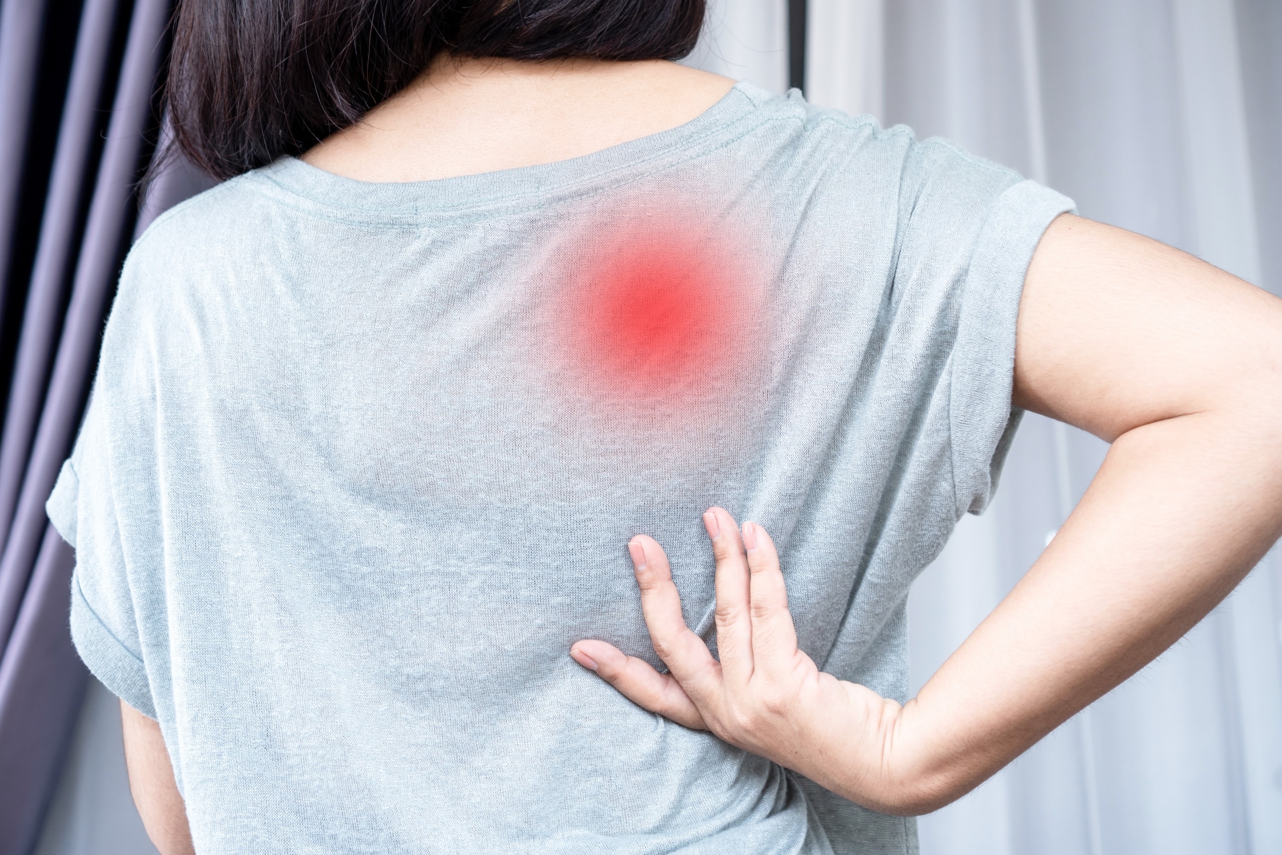 Woman in a grey shirt with back pain