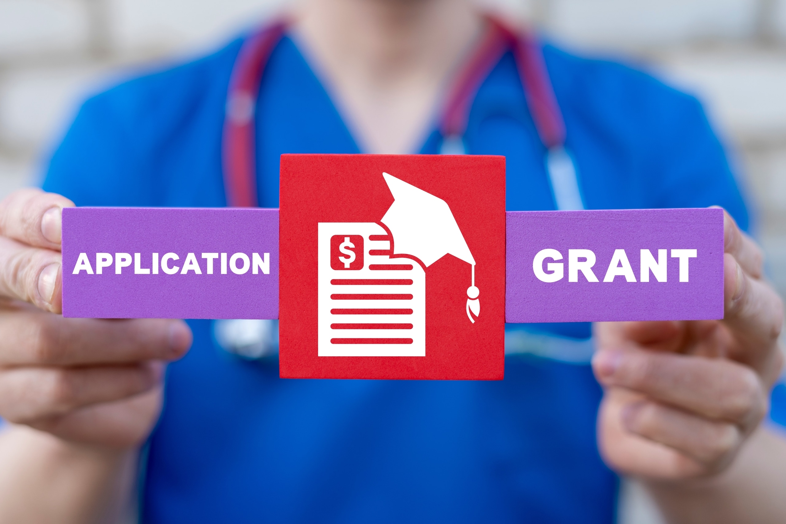 Close up of a nurse holding blocks that say grant and application