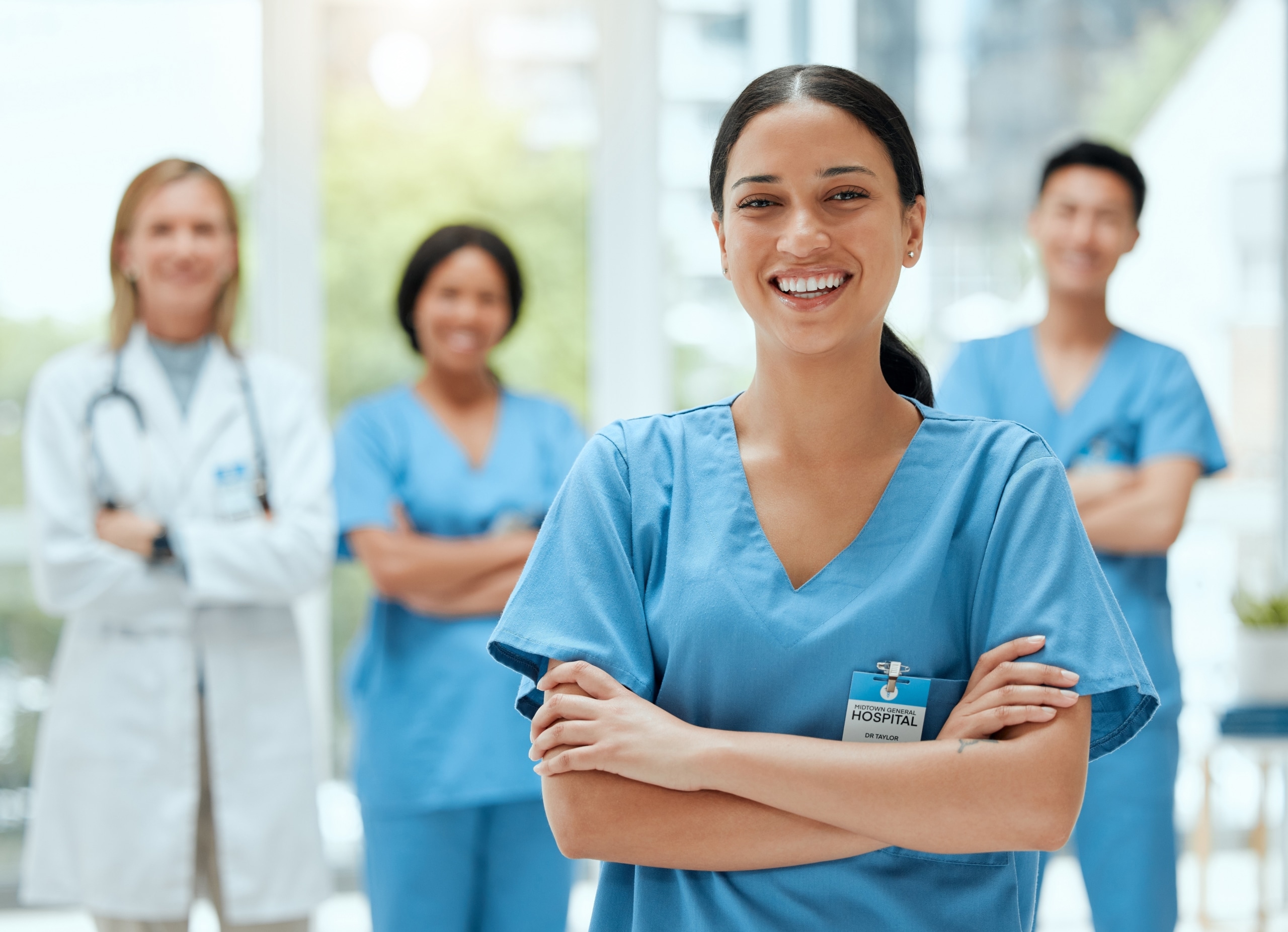 Smiling nurse standing in front of other medical professionals
