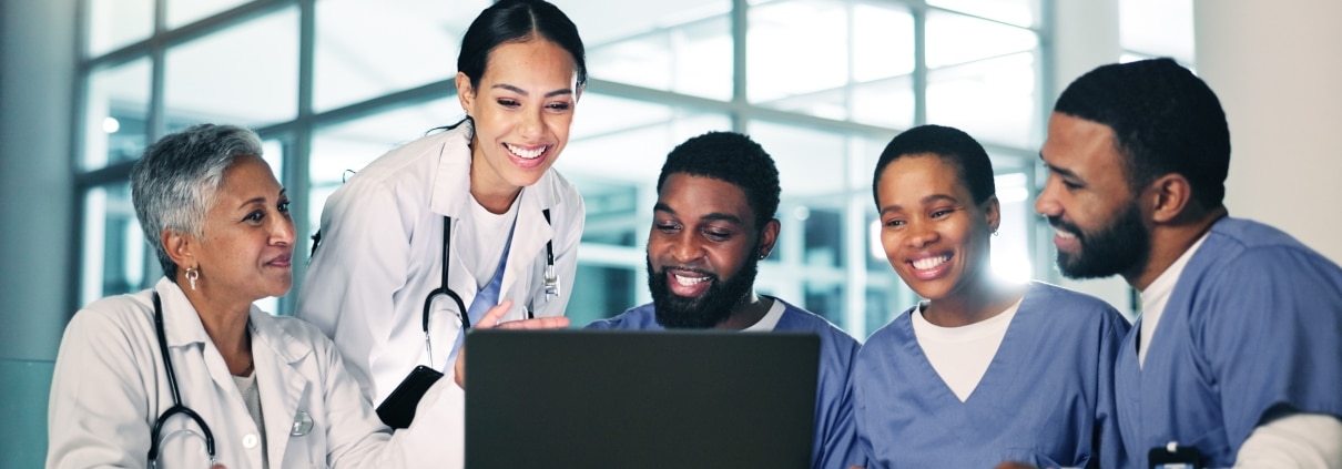 Medical professionals standing around a laptop