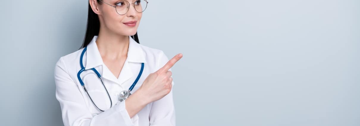Professional nurse pointing to the side against a solid backdrop