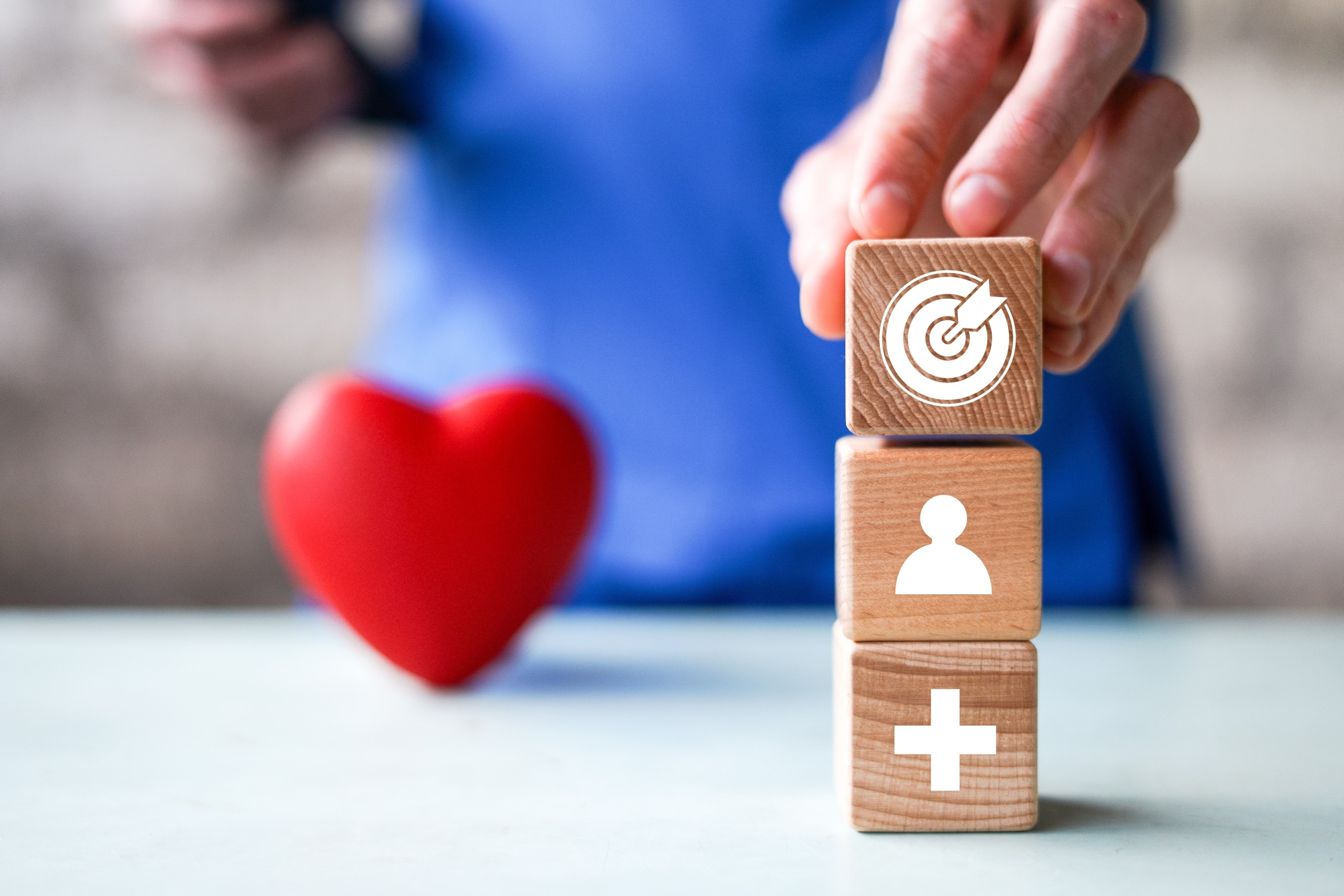 Close up of a nurse next to a miniature heart and blocks with healthcare symbols