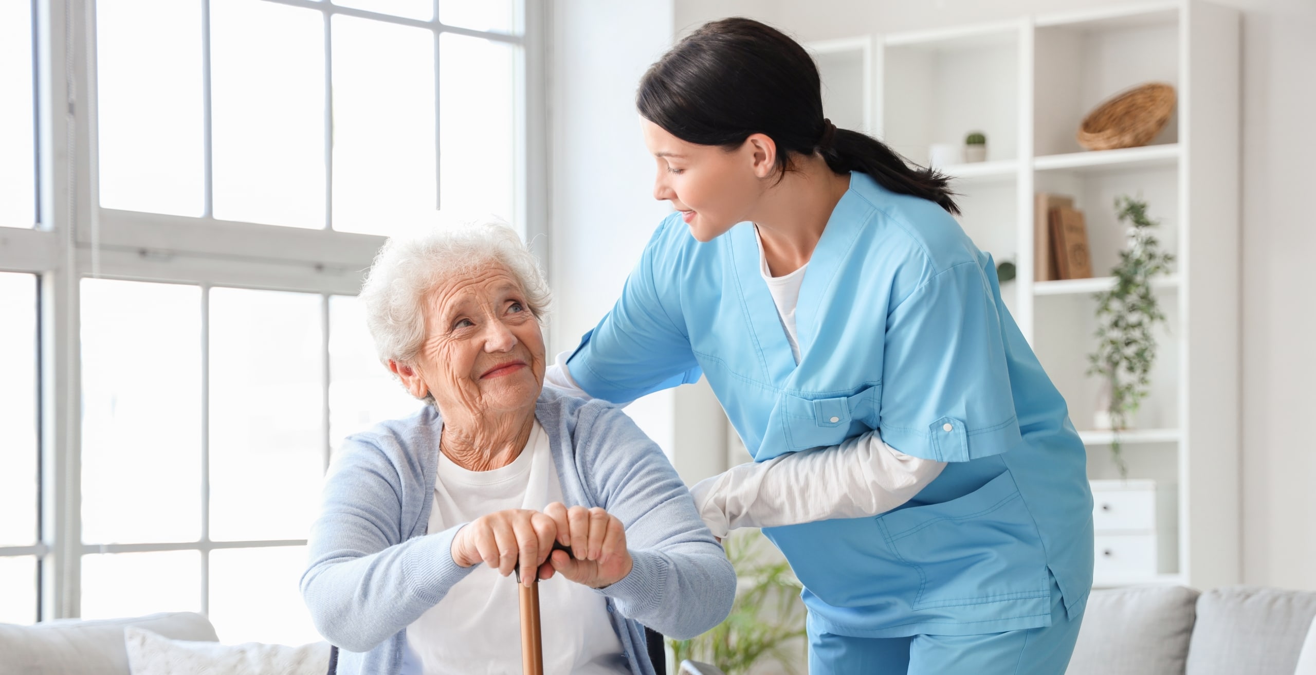 Senior woman with kind nurse in scrubs