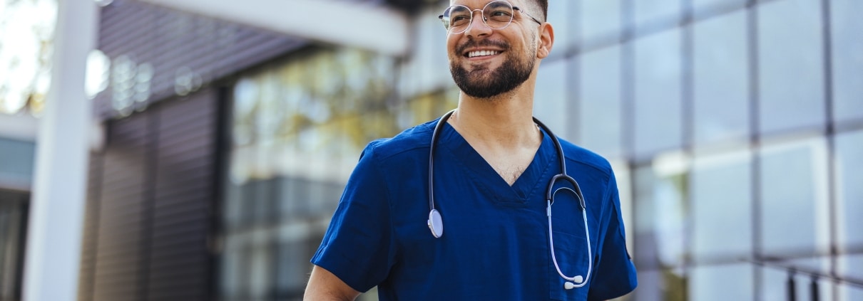 Joyful male nurse standing outside a hospital