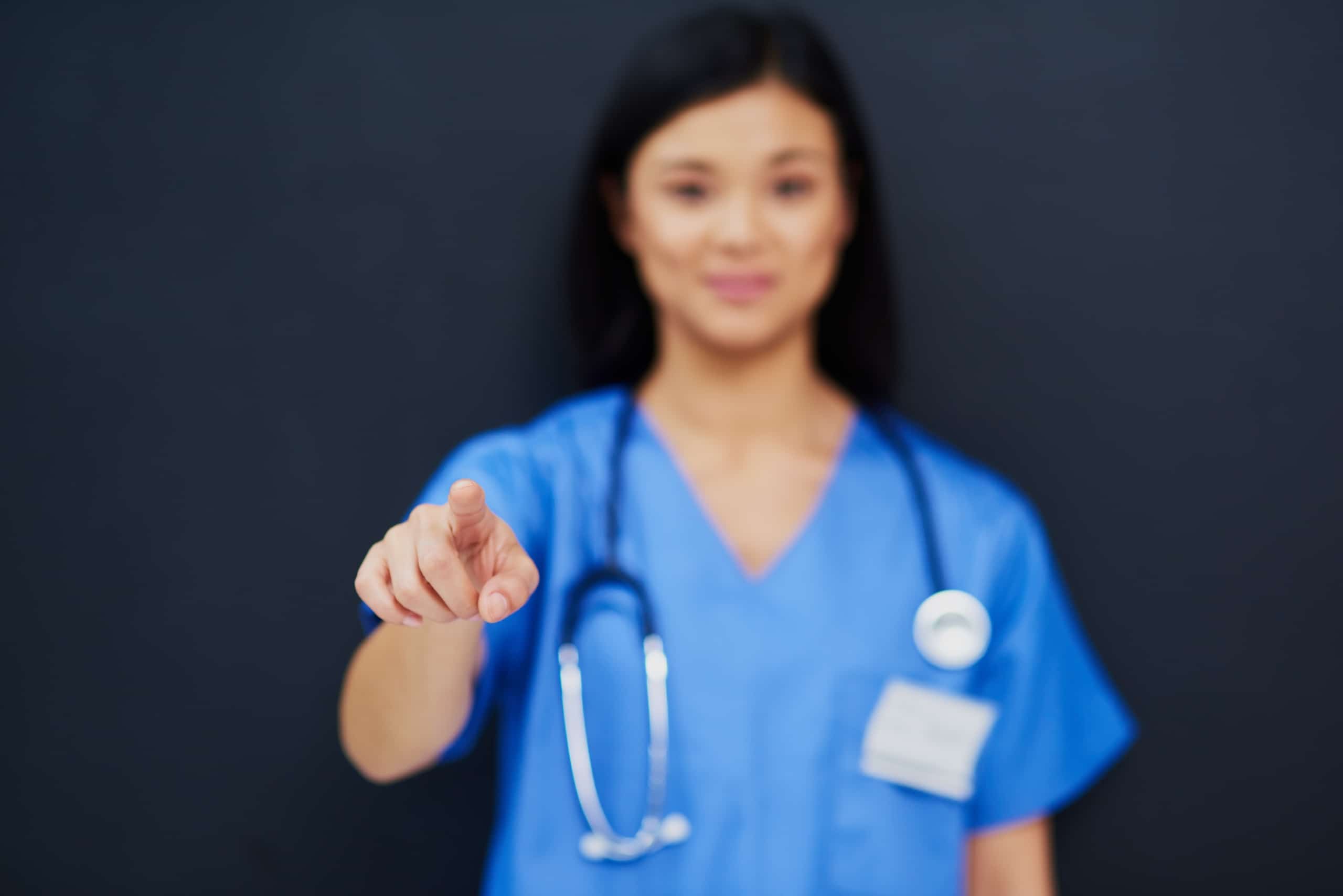 Asian nurse pointing toward the camera