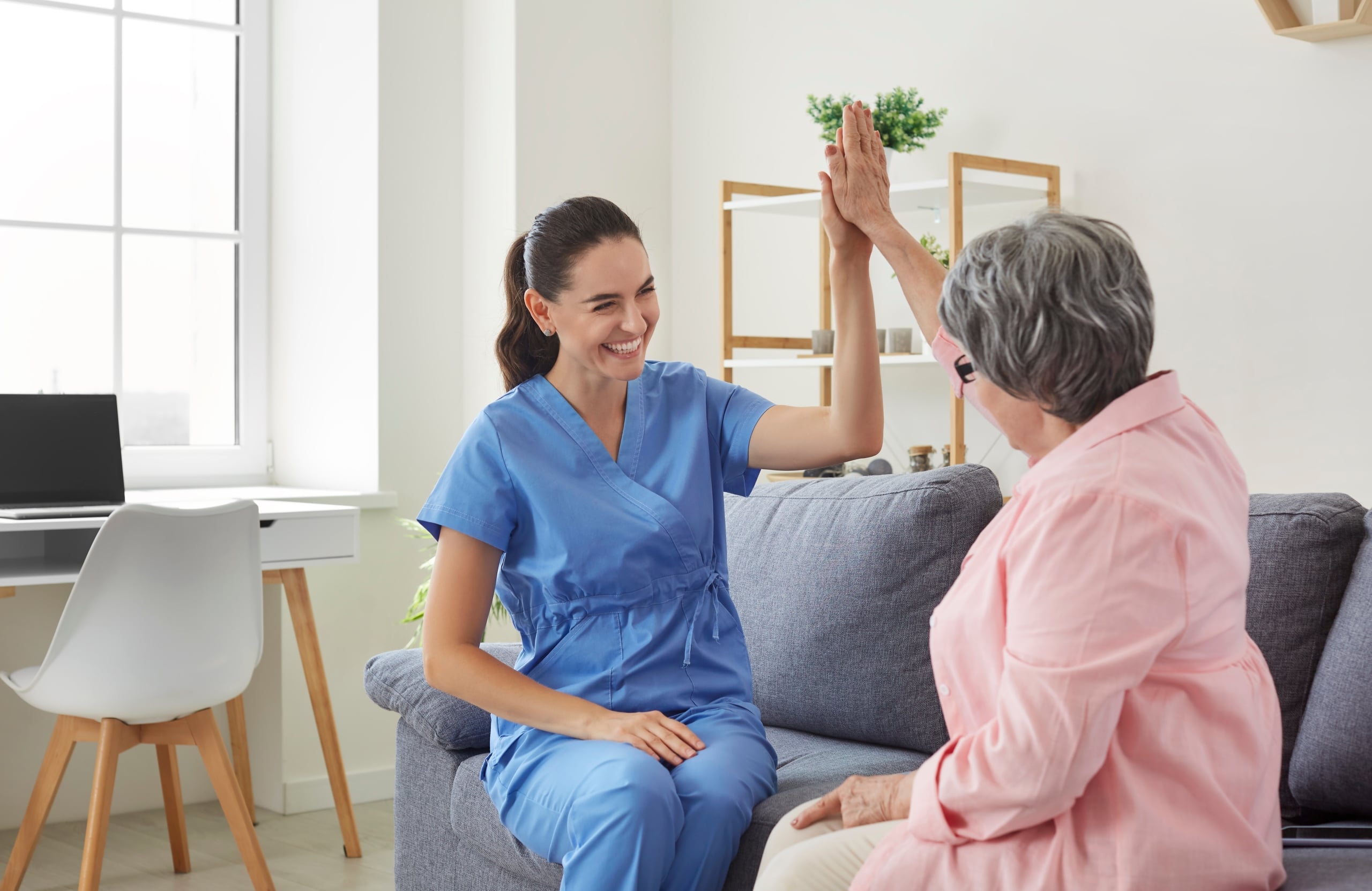 Cheerful medical professional high fiving an older woman