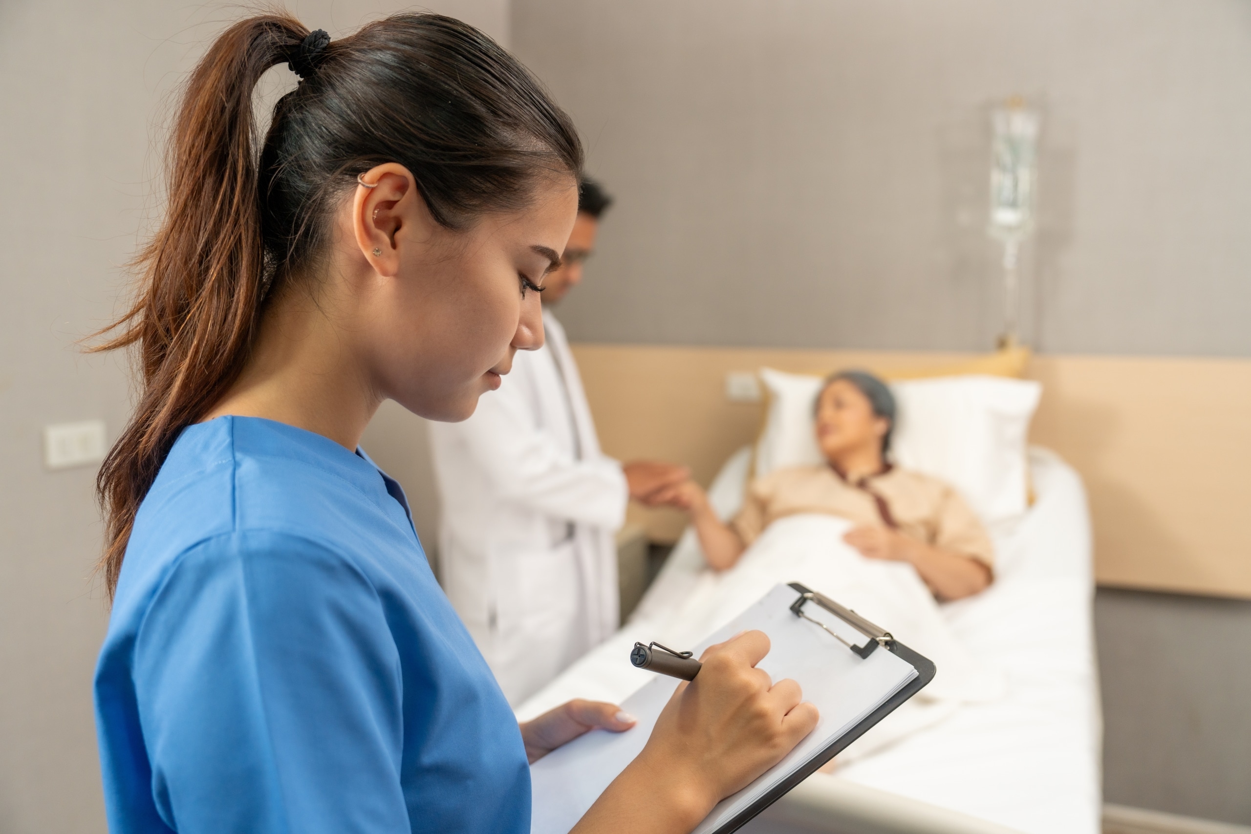 Nurse taking notes while a doctor speaks with a patient