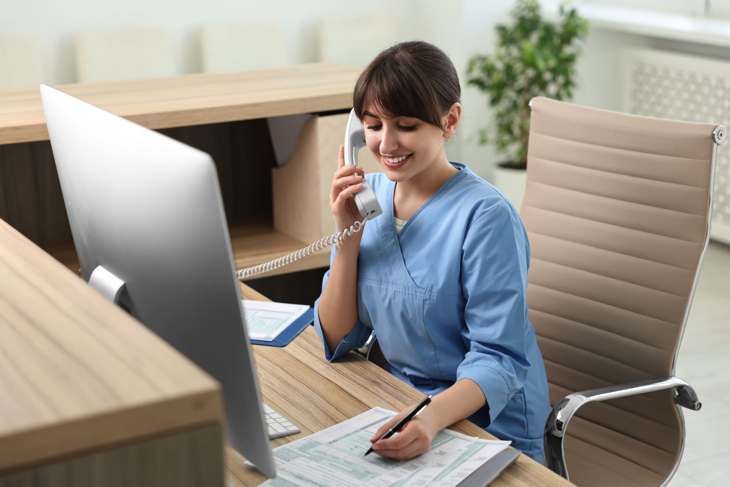 Medical Assistant sitting at a desk and speaking on the phone