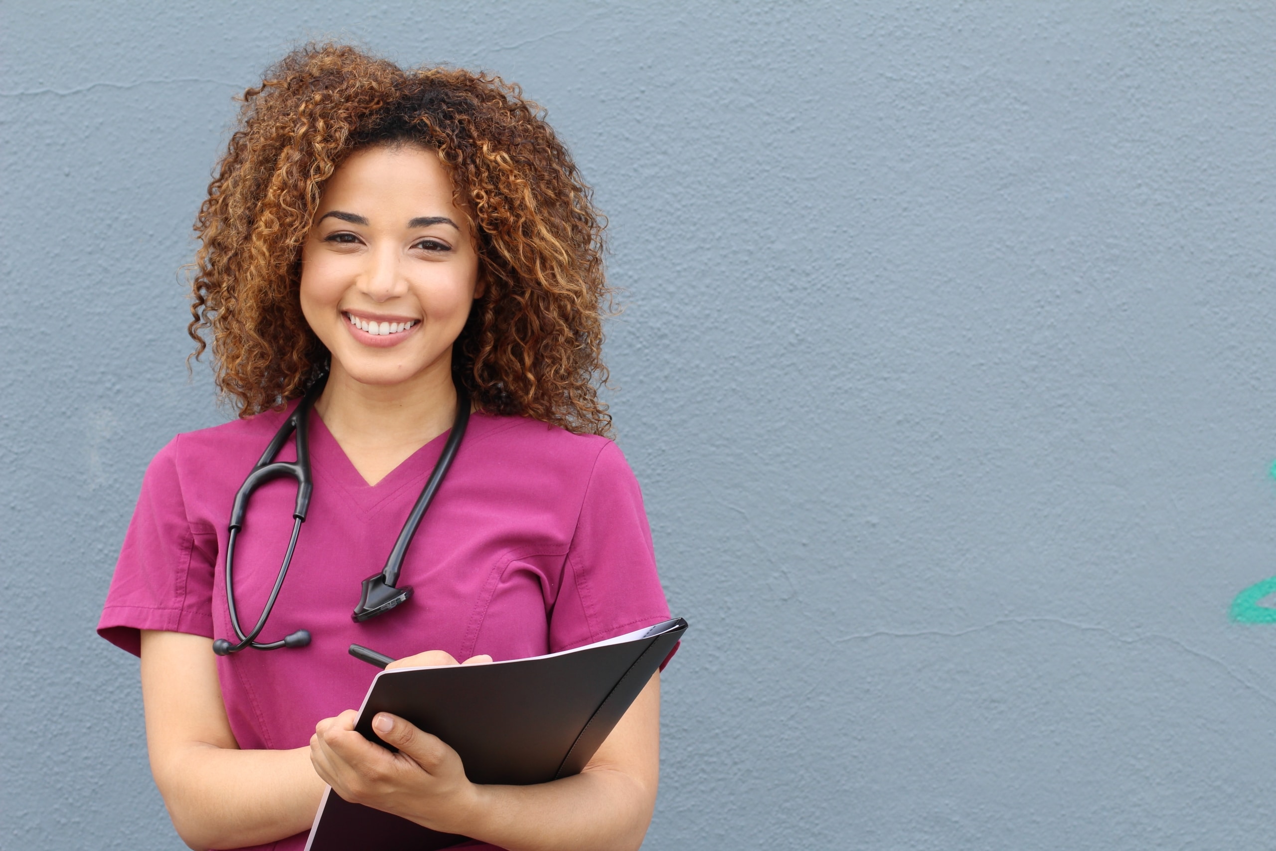 African-American nurse in pink scrubs with a clipboard