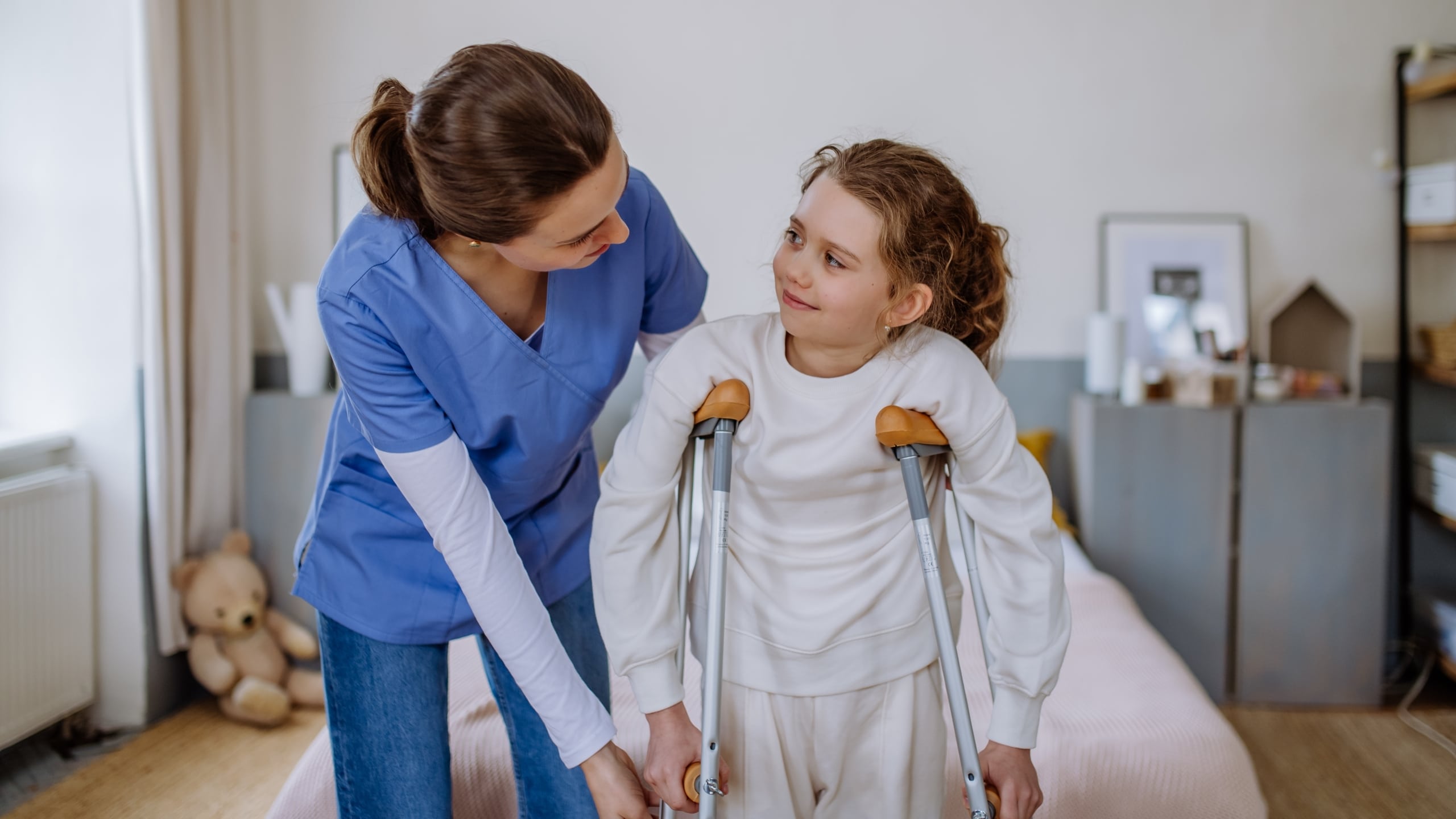 Young medical professional helping a child use crutches