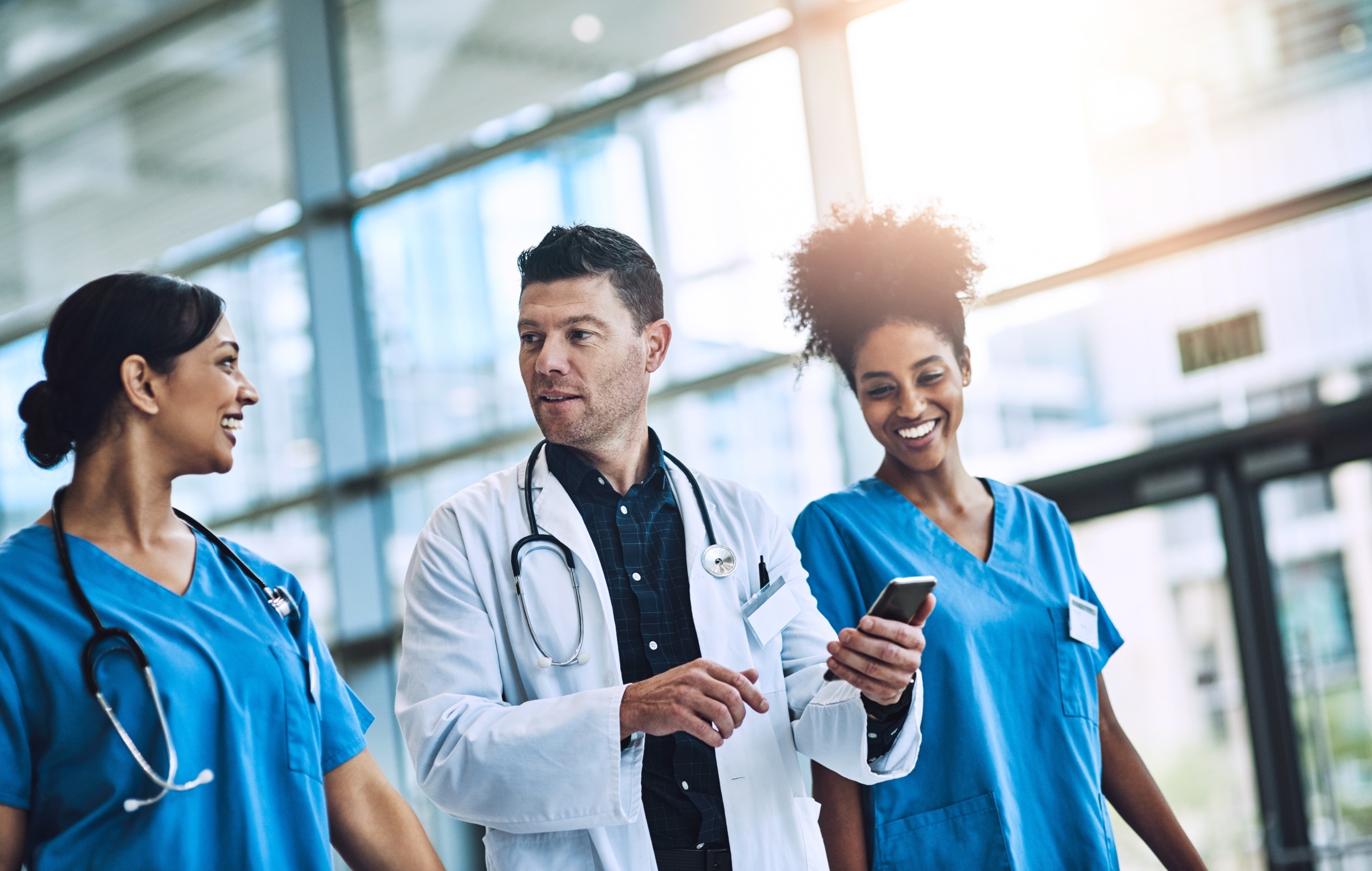 Three medical professionals walking in a hospital hallway